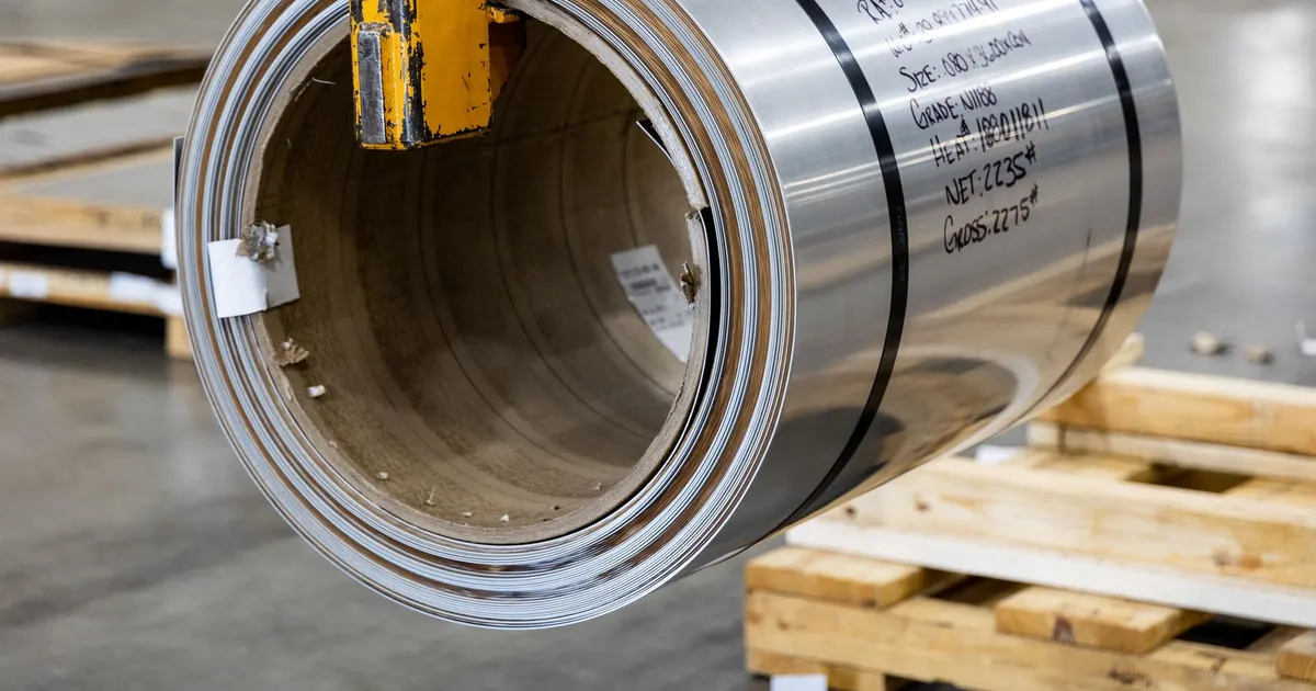 Large coil of rolled aluminum strip on a wooden pallet in a warehouse