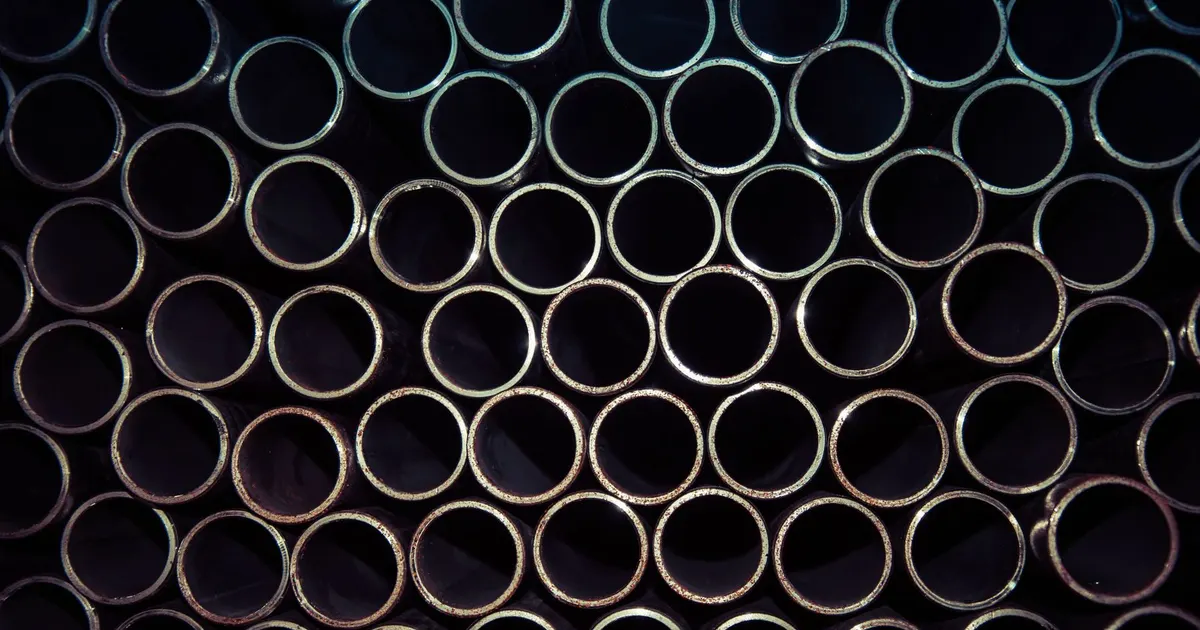End view of many round steel tubes stacked together in a warehouse