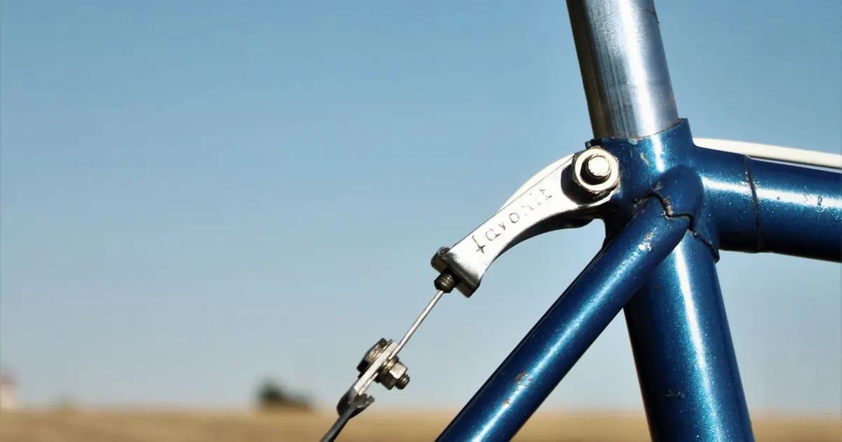 Seat tube and seatpost binder clamp on a blue steel bicycle frame against a clear sky